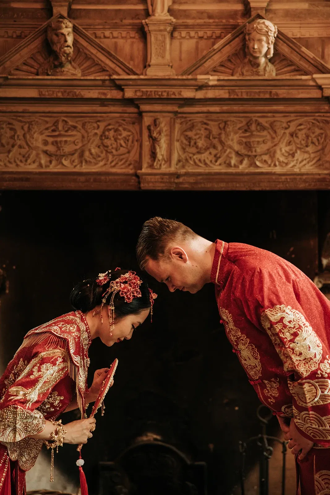 Bruidspaar in traditionele Chinese kleding buigt naar elkaar.