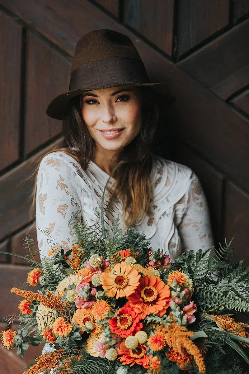 boho-bruid met hoed en kleurrijke bloemen.