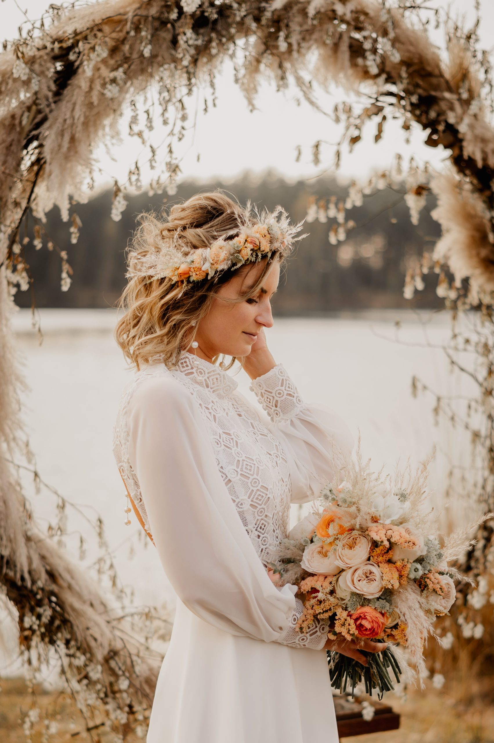 boho-bruid met bloemenkroon voor pampasgras boog