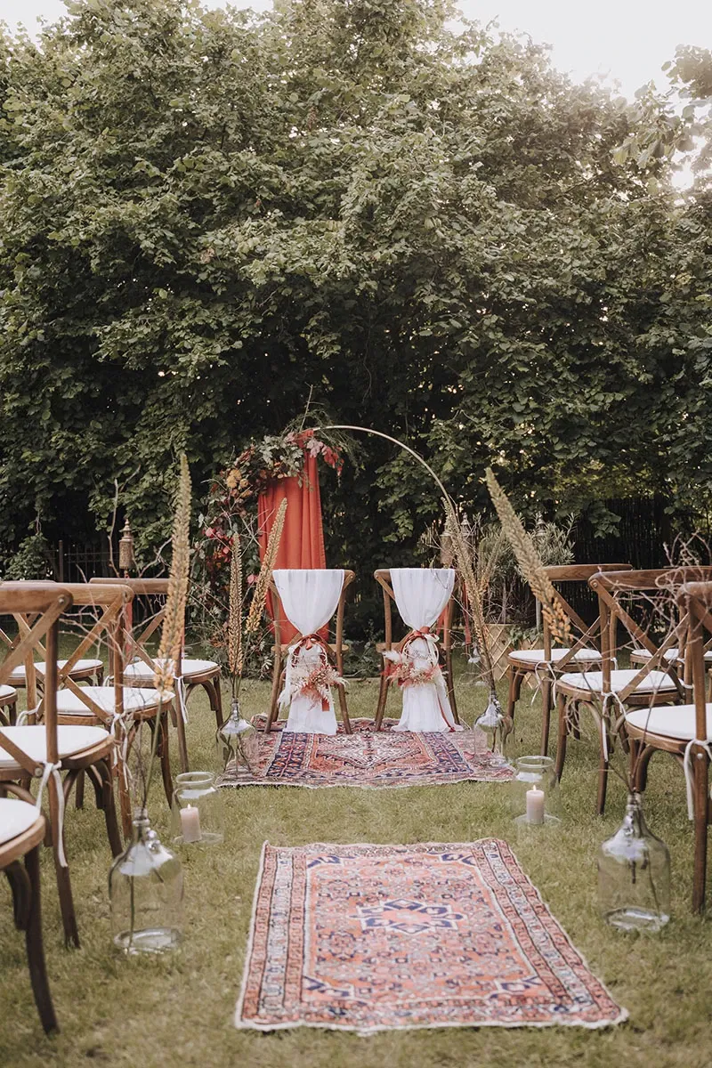 boho-bruiloft ceremoniesetting met vintage kleden en boog