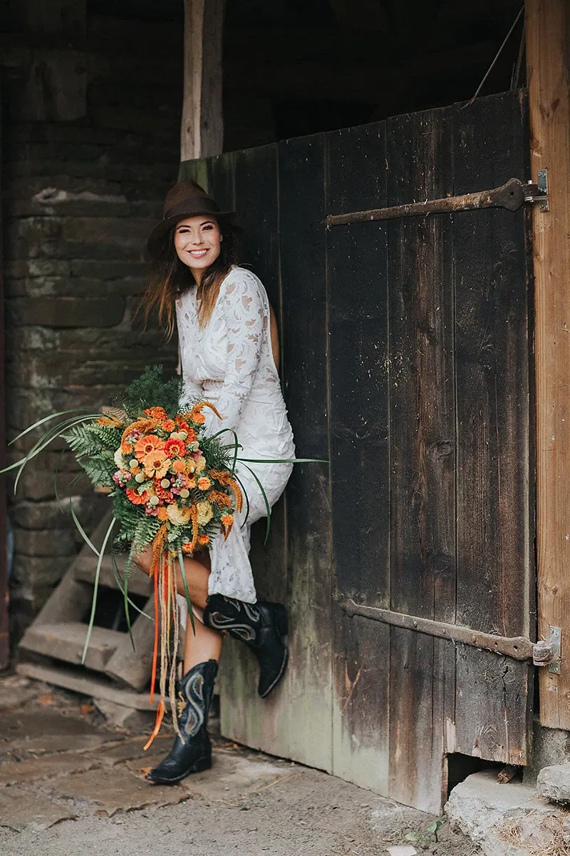 boho-bruid met hoed, kanten jurk en cowboylaarzen