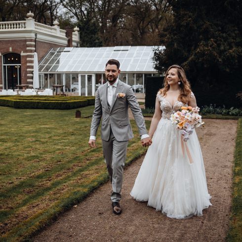 Bruidspaar loopt hand in hand in tuin van trouwlocatie Groot Warnsborn