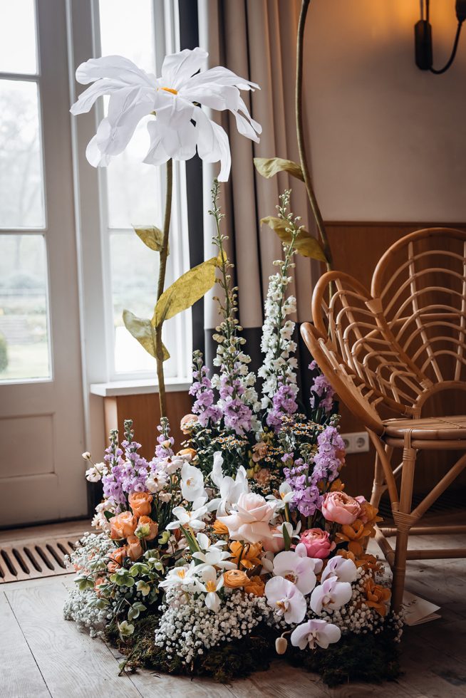 Prachtige kleurrijke bloemen en witte XXL-bloem bij stoel in ceremoniesetting.