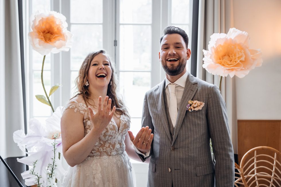 Bruidspaar laat trots hun trouwringen zien