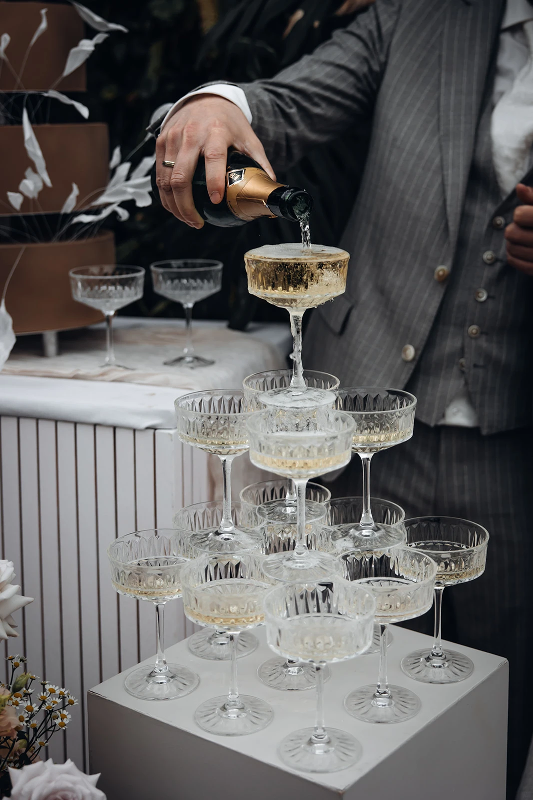 Bruidegom schenkt champagne in bovenste glas champagnetoren.