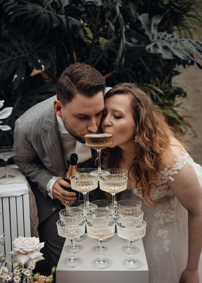 Bruidspaar drinkt champagne uit bovenste glas champagnetoren