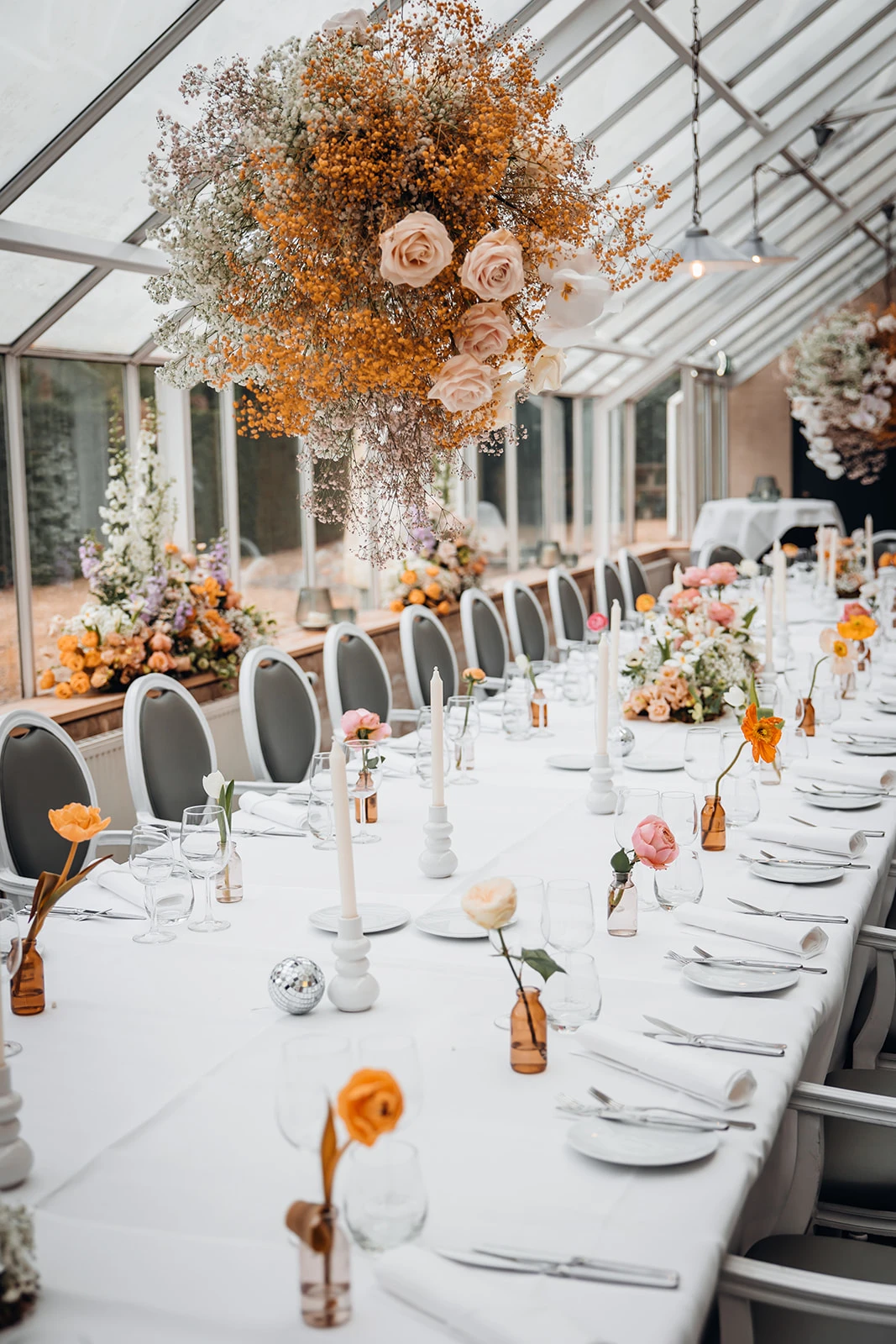 Lange eettafel gedekt en versierd met kleurrijke bloemen