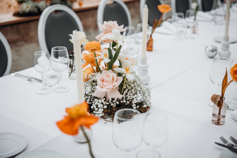 Lange eettafel gedekt en versierd met kleurrijke bloemen