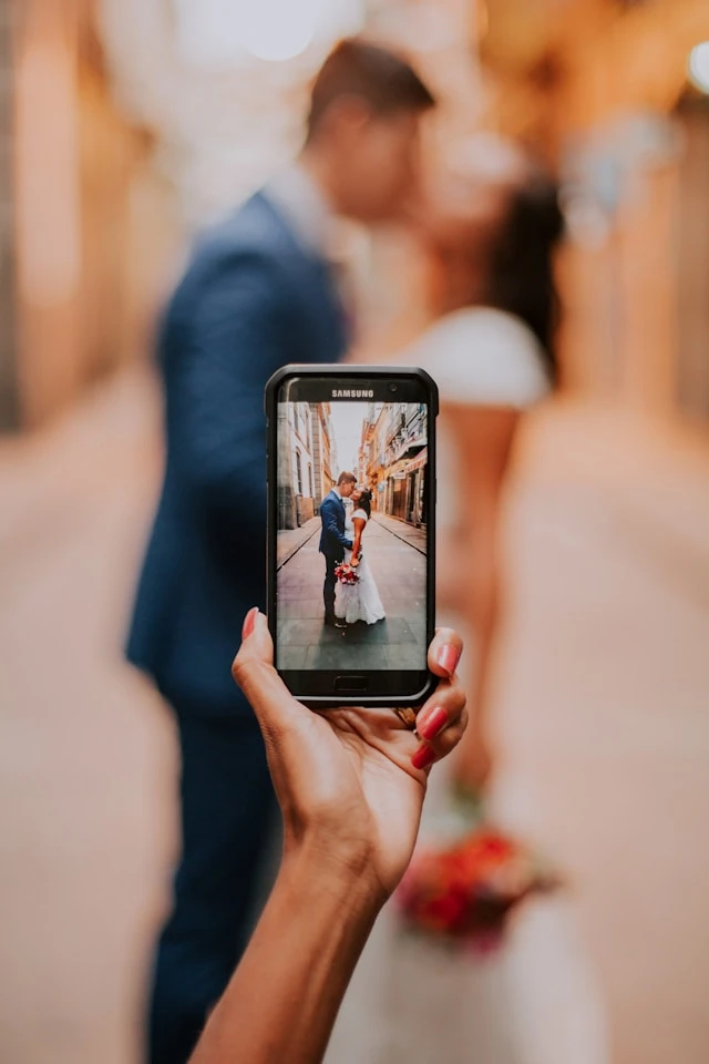 Gast maakt foto met Samsung telefoon van bruidspaar