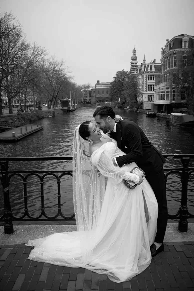Bruidspaar kussend op grachtenbrug Amsterdam