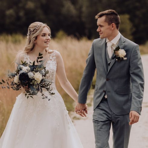 bruidspaar loopt hand in hand in de natuur