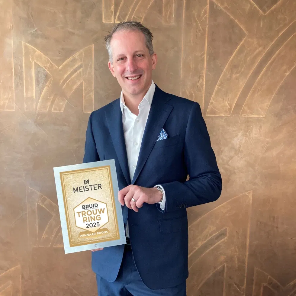 Man in pak met een award in zijn hand.