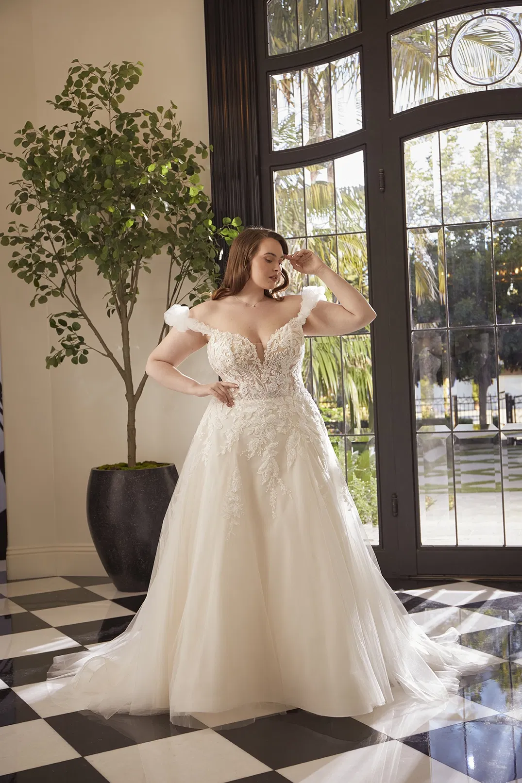 bruid in trouwjurk met appliques, lage v-hals en off the shoulder mouwtjes. Verder heeft de bruidsjurk een a-lijn rok van tule.