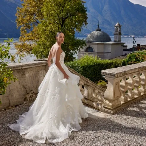 Bruid in een witte bruidsjurk met op de achtergrond mooie bergen en een meer.