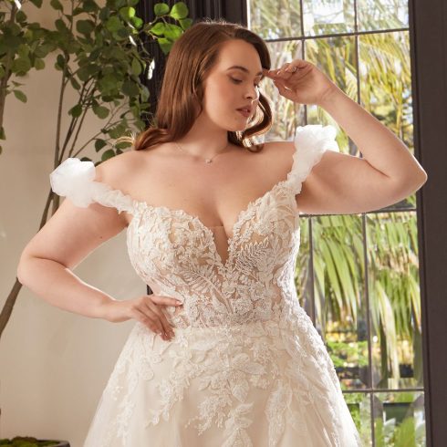 bruid in trouwjurk met appliques, lage v-hals en off the shoulder mouwtjes. Verder heeft de bruidsjurk een a-lijn rok.