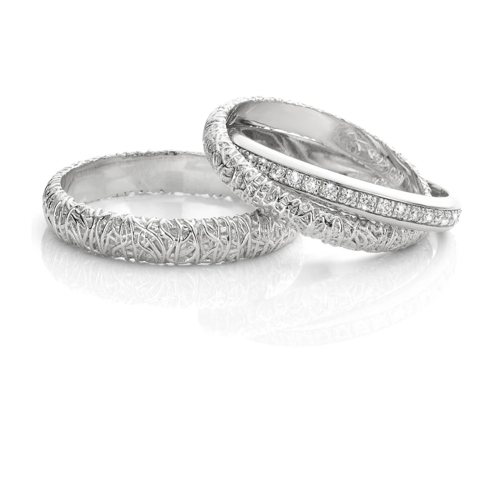 Twee unieke witgouden trouwringen met een organisch, verweven ontwerp. Eén ring is gedetailleerd met een rij sprankelende diamanten voor extra elegantie.