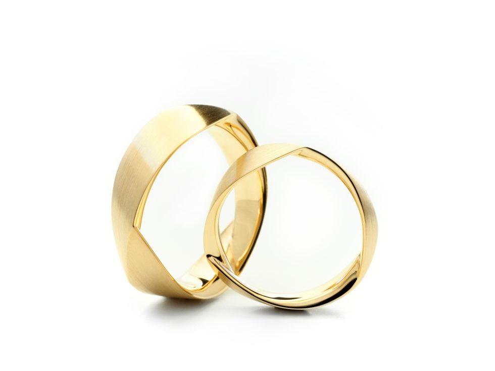 Twee gouden trouwringen met een moderne, geometrische vormgeving.