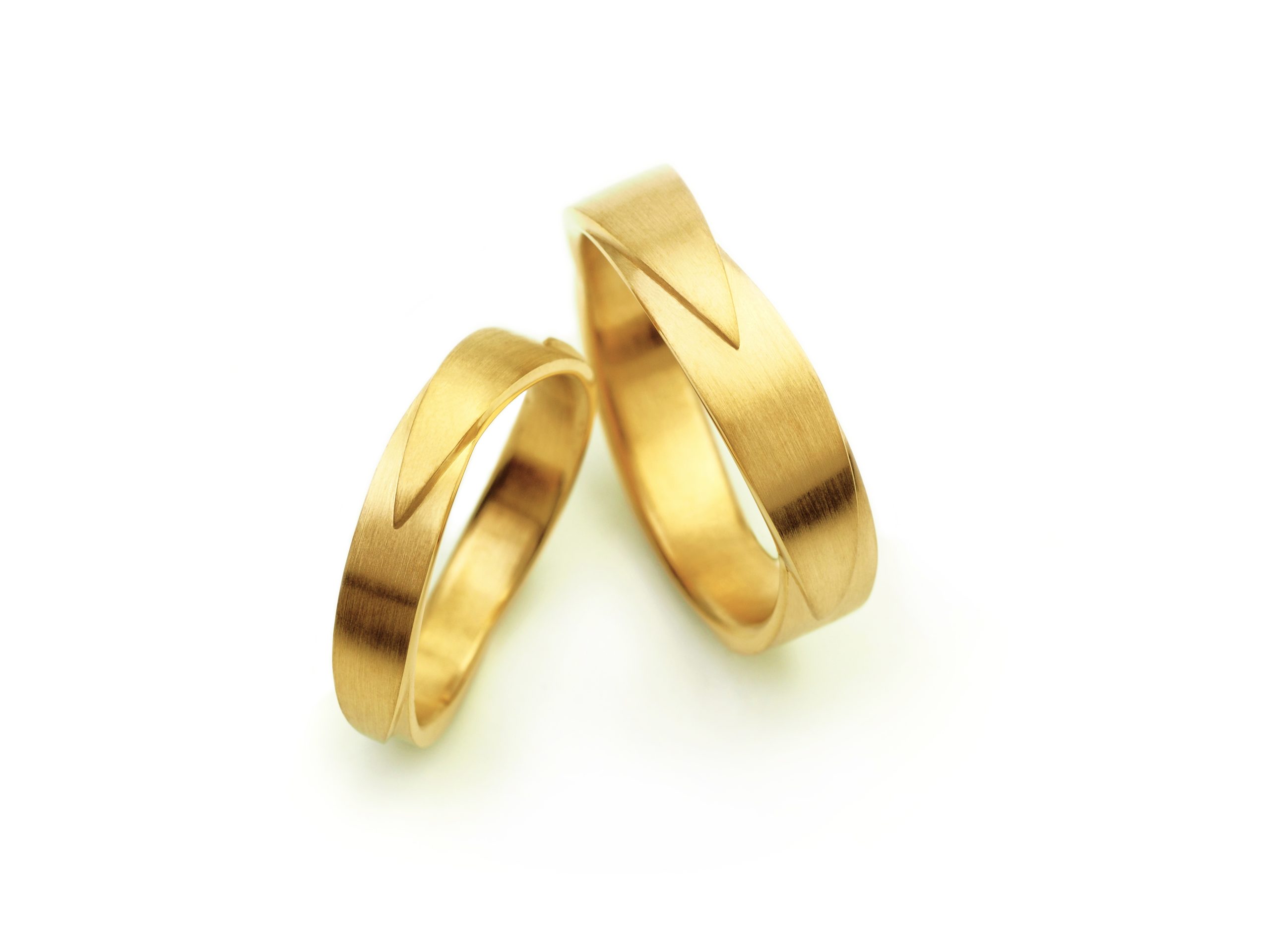 Twee gouden trouwringen met een strak, geometrisch ontwerp en een vleugelachtige curve.