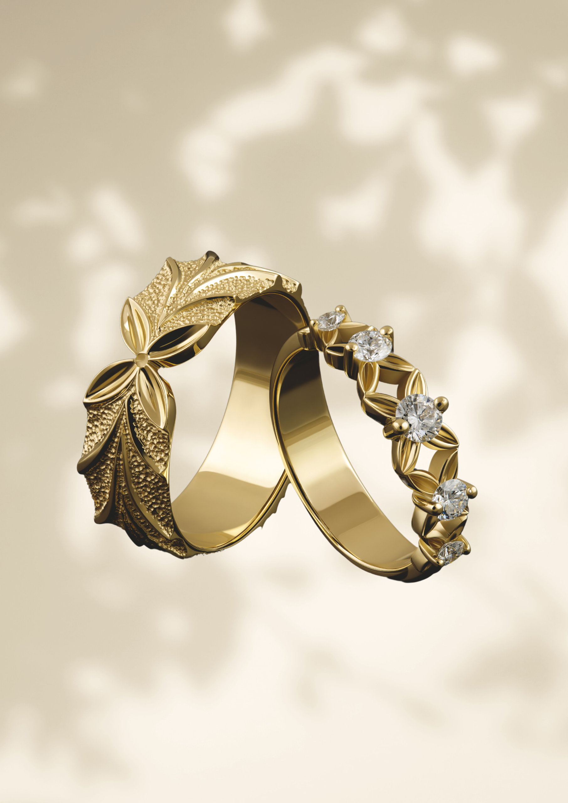 Een set elegante gouden trouwringen met een verfijnd natuurmotief. De ene ring heeft een gedetailleerd bladpatroon met een gestructureerde afwerking, terwijl de andere is versierd met fonkelende diamanten en delicate bladvormige zettingen. De ringen zweven sierlijk tegen een zachte, neutrale achtergrond met schaduwpatronen.