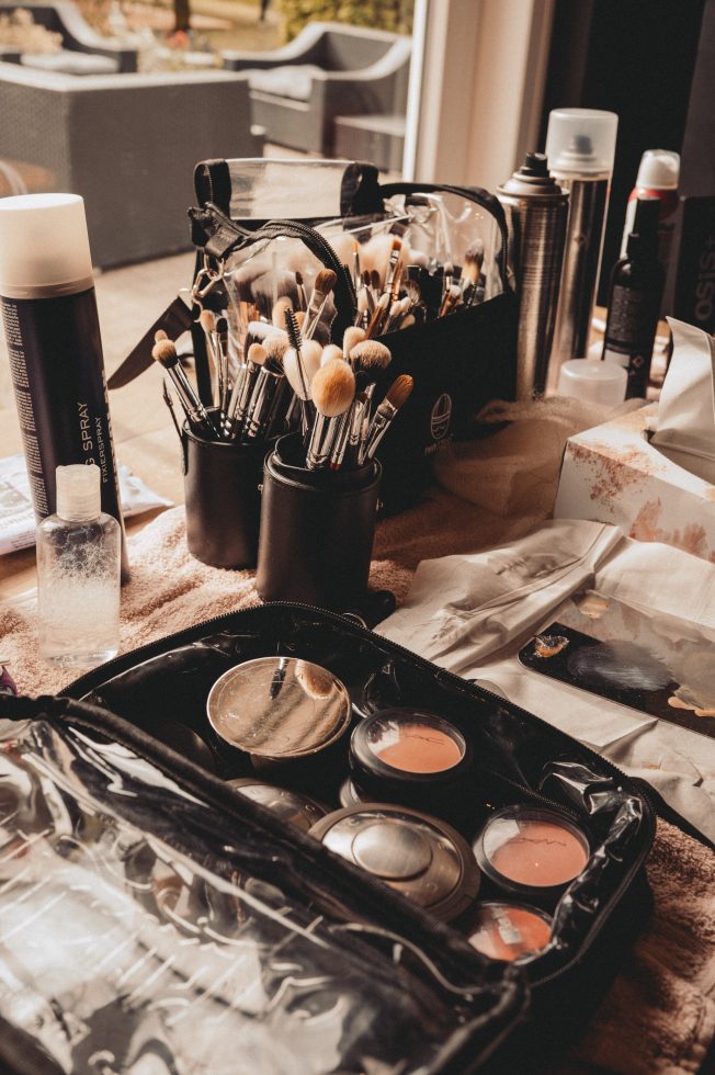 Close-up van een make-up tafel met professionele kwasten, blush, fixing spray en visagieproducten, klaar voor het stylen van een bruid tijdens een bruiloft of fotoshoot.