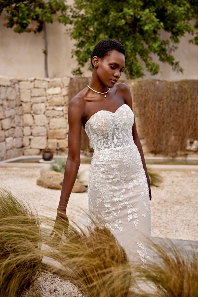 Donker getinte bruid in een witte strakke trouwjurk met een sweetheart halslijn.