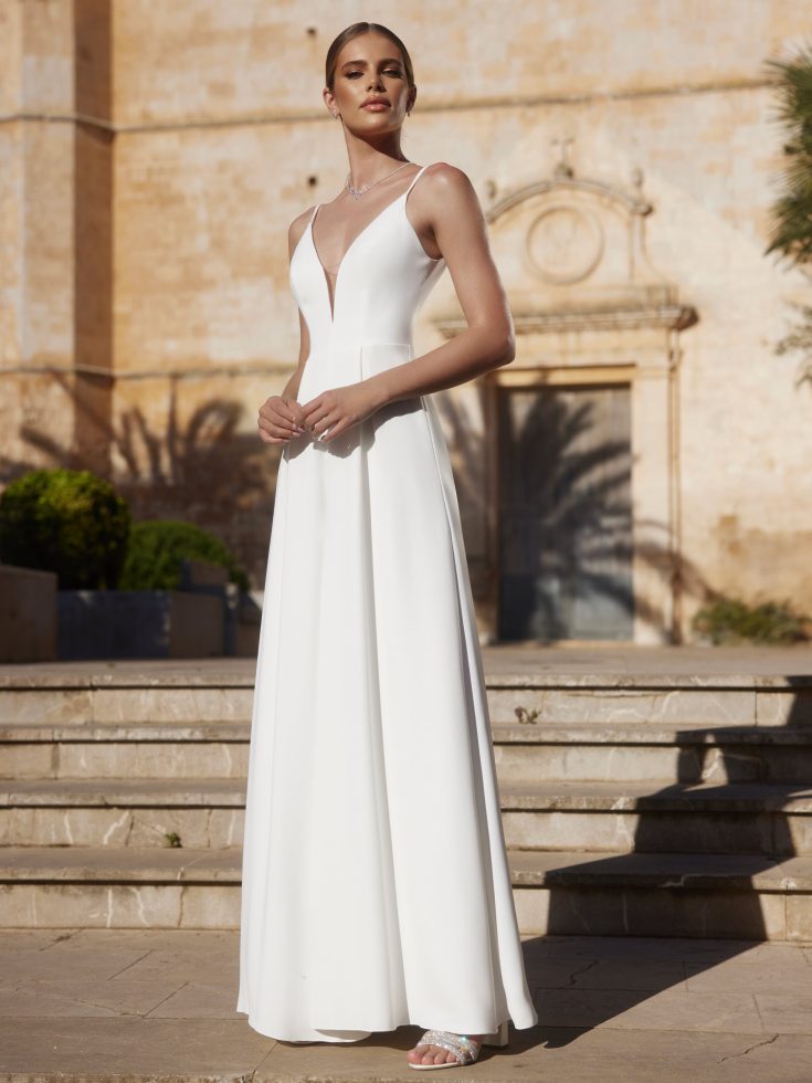 Bruid poseert op een trap. Ze heeft een wit trouwjumpsuit aan van Bianco Evento.