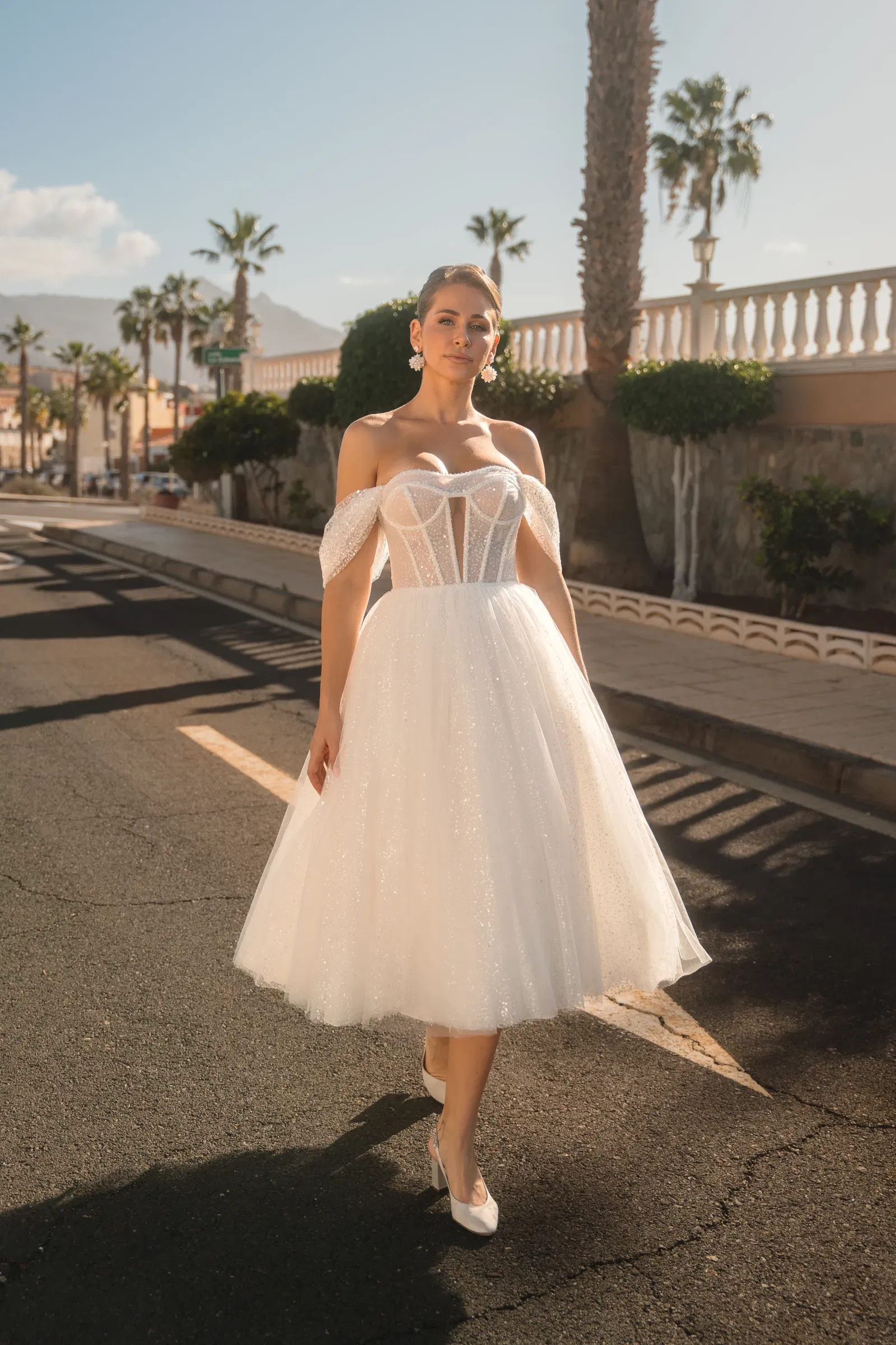 Korte witte trouwjurk met een rok van tule. Off shoulders bandjes met een strakke top.