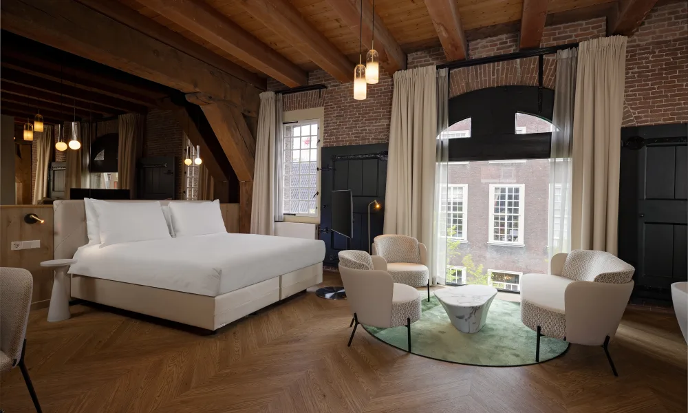 Luxe hotelkamer in Hotel Arsenaal in Delft met houten balkenplafond, designmeubels en grote ramen met uitzicht op het historische centrum.