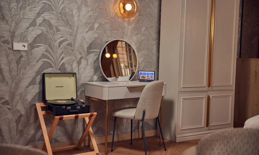 Detail van luxe hotelkamer in Hotel Arsenaal in Delft met retro platenspeler, design kaptafel en stijlvolle behangaccenten.
