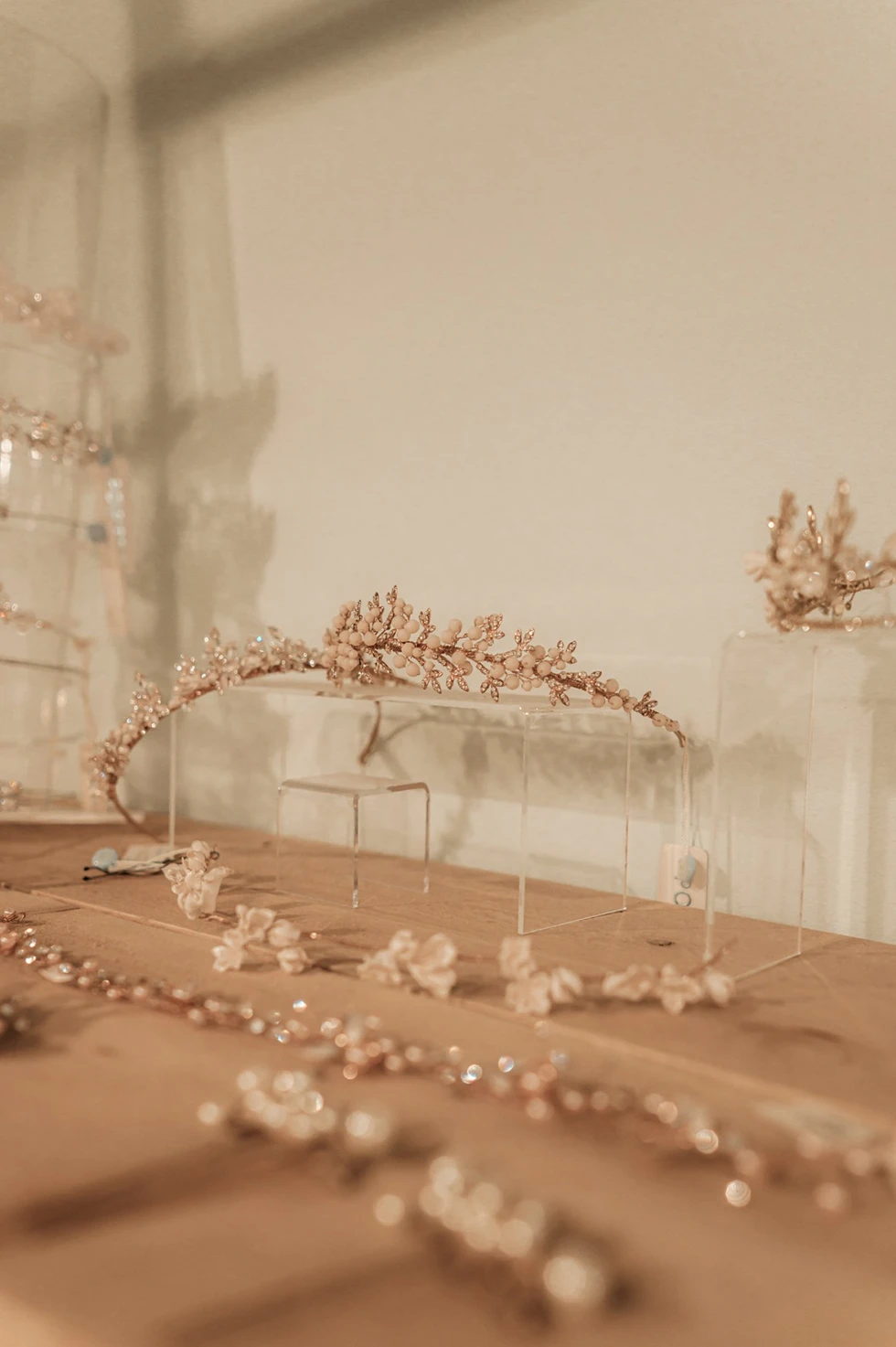 Fijne bruidsaccessoires zoals haarsieraden en tiara’s in roségoud op een houten tafel gepresenteerd.