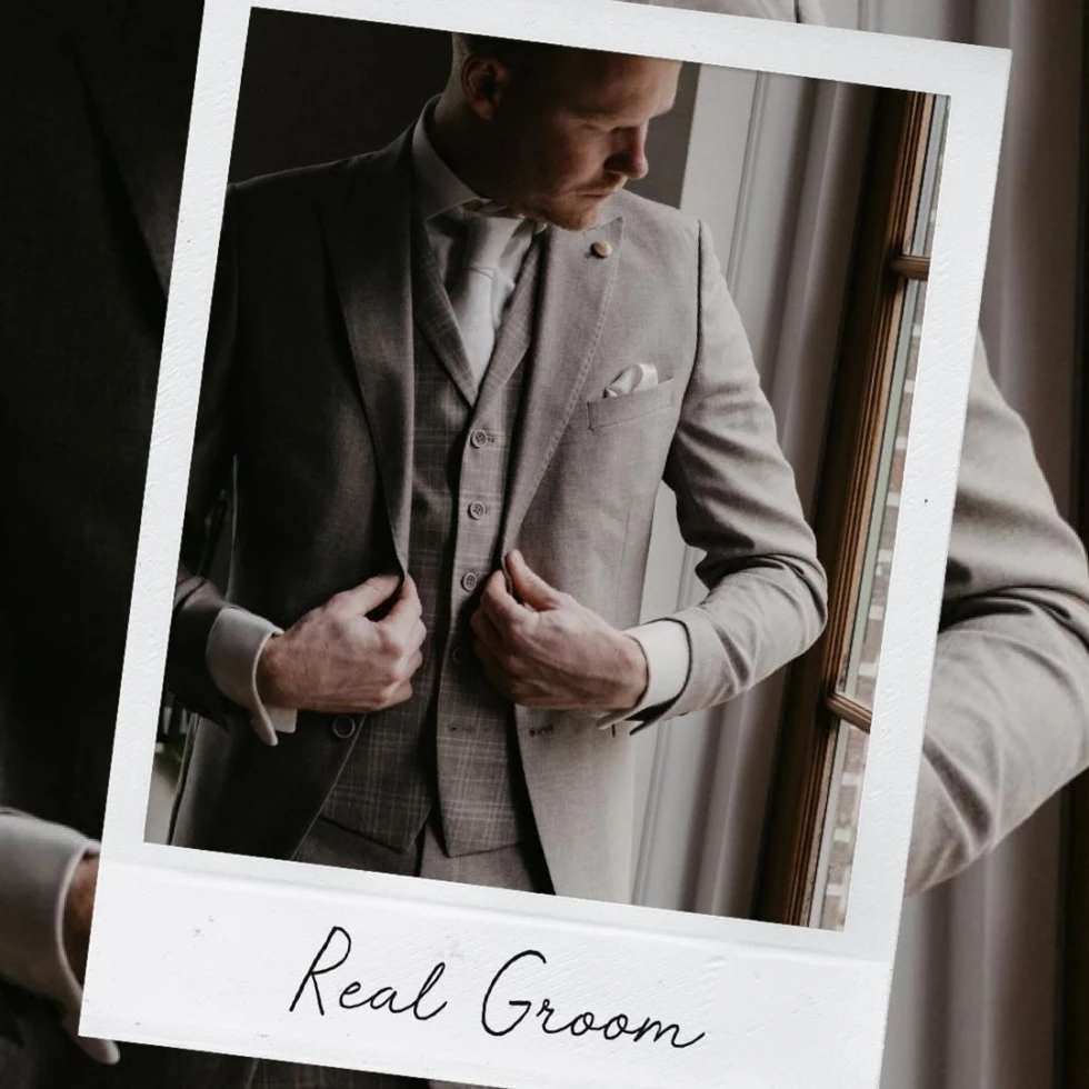 ruidegom in beige trouwpak met gilet en pochet voor het raam