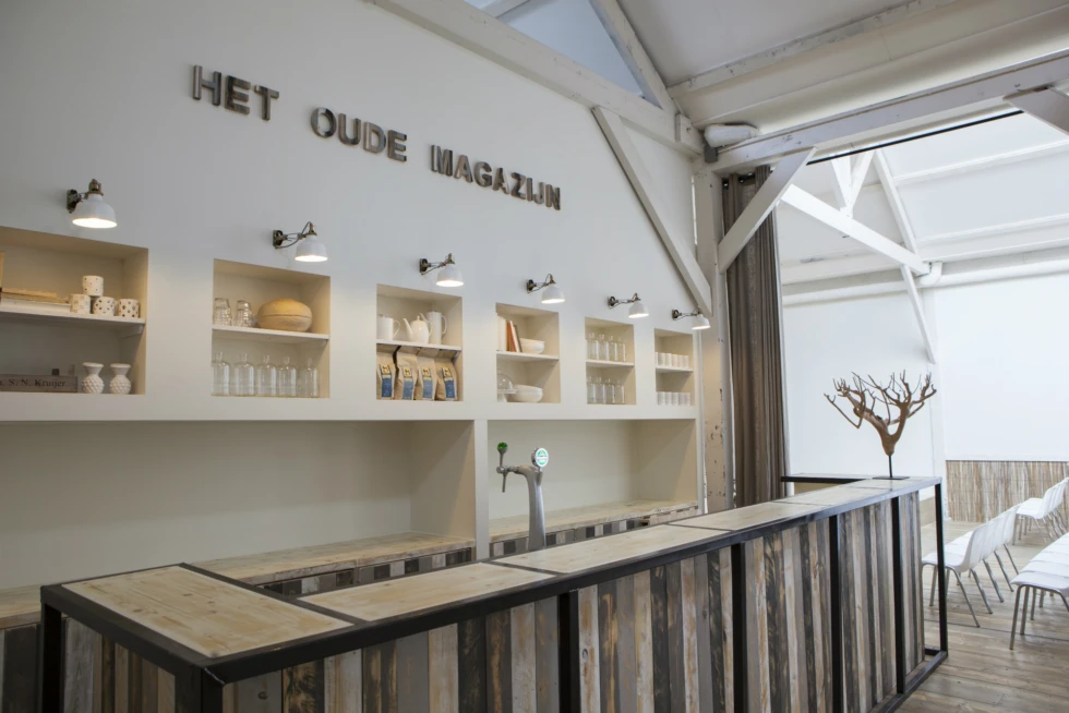 De bar in Het Oude Magazijn ademt een robuuste en sfeervolle uitstraling dankzij het gebruik van hout, staal en neutrale tinten. Ideaal voor een gezellige borrel na de ceremonie of een feestelijke afsluiting van jullie trouwdag.