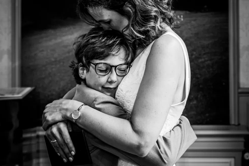 Moeder drukt haar zoontje liefdevol tegen zich aan in ontroerende bruiloftsomhelzing.