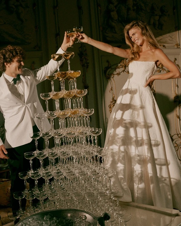 Bruidspaar proost met elkaar terwijl ze bij een champagnetoren staan.