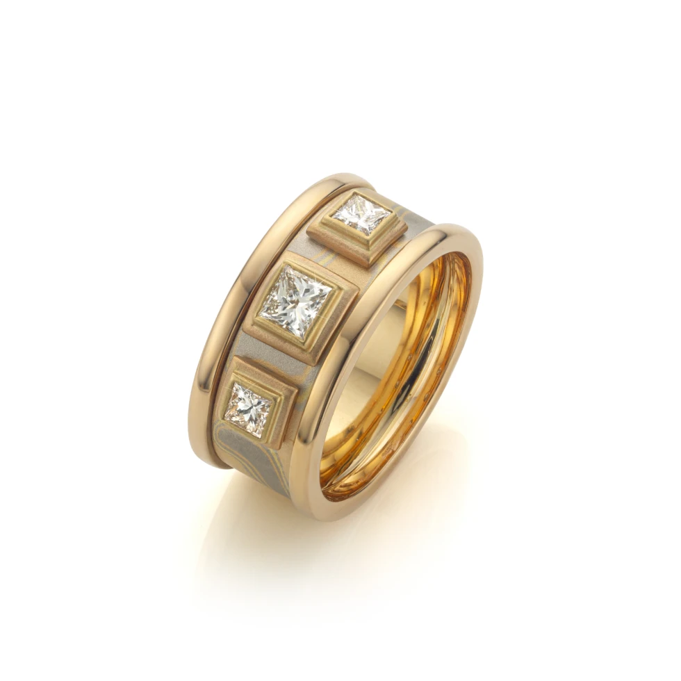 Exclusieve mokume gane ring met drie princess geslepen diamanten in vierkante zettingen en gepolijste randen.