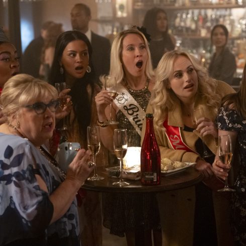 Een groep vrouwen zitten tijdens een vrijgezellenfeest in een kroeg en kijken heel verbaasd en geschrokken een kant op.