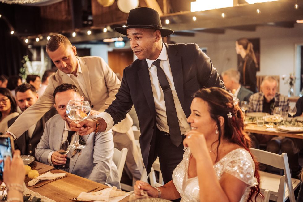 Goochelaar verrast bruidspaar en gasten met een magische act tijdens een bruiloftsreceptie.