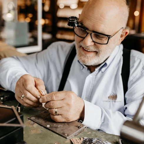 Goudsmid bewerkt trouwring aan werkbank in ambachtelijke atelier.