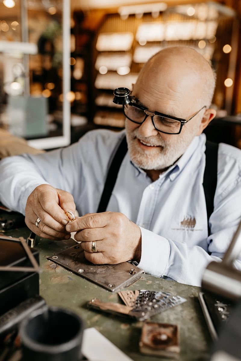 Goudsmid bewerkt trouwring aan werkbank in ambachtelijke atelier.