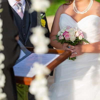 Bruid en bruidegom tijdens huwelijksceremonie, bruid met boeket en parelketting.