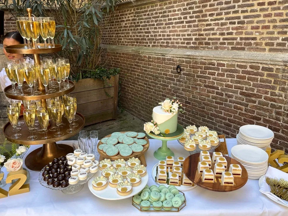 Sweet table met bruidstaart, gebakjes en macarons in mintgroene en gouden tinten, feestelijk opgesteld in buitenruimte