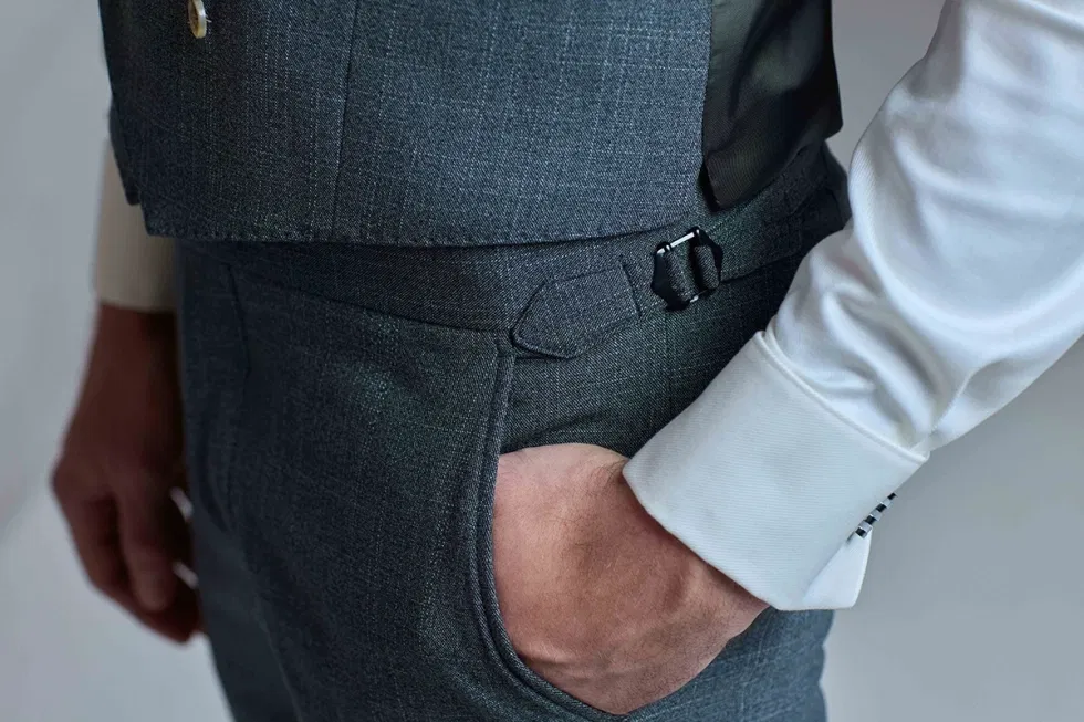 Close-up van donkergrijs trouwpak met hand nonchalant in de broekzak.