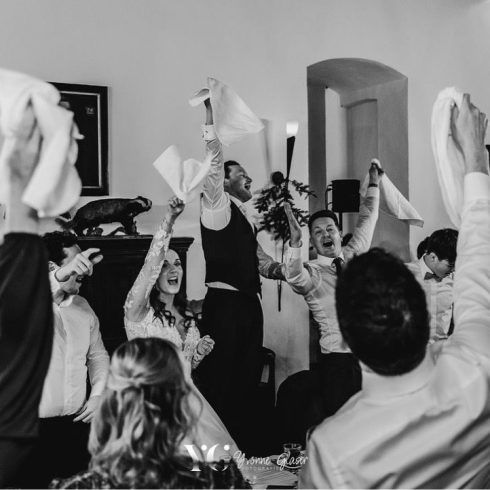 Zwart-wit afbeelding van mensen die springen en in hun hand een servet vasthouden en die ronddraaien.