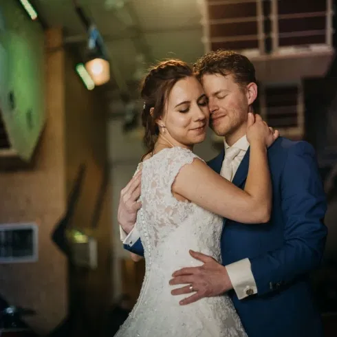 Bruid en bruidegom in een intieme omhelzing met gesloten ogen op hun trouwdag.