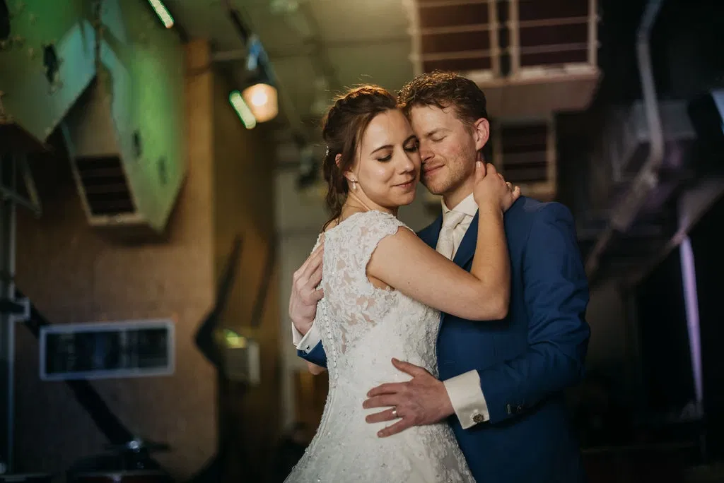 Bruid en bruidegom in een intieme omhelzing met gesloten ogen op hun trouwdag.