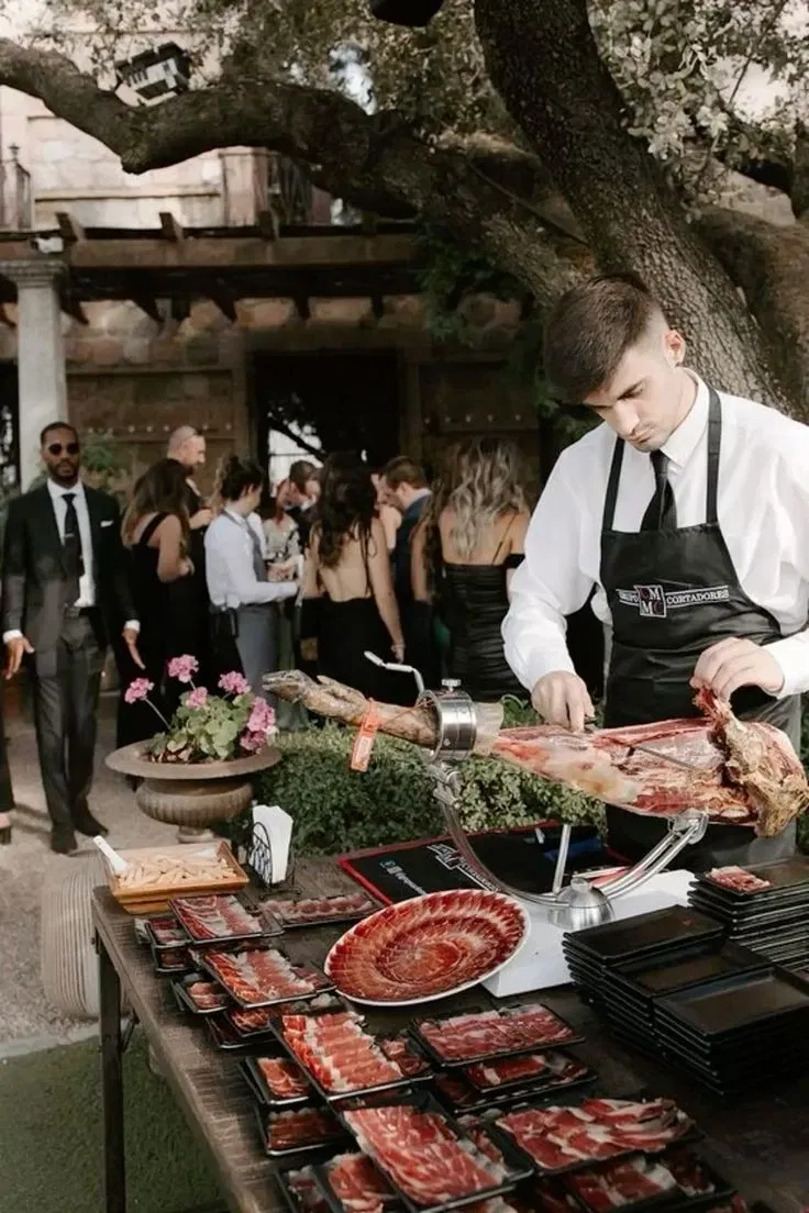 Man die op een bruiloft live iberico ham aan het snijden is voor gasten.