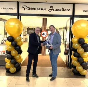 Twee mannen schudden elkaar de hand voor een winkel met een bordje 40 erop van Puttmann juweliers