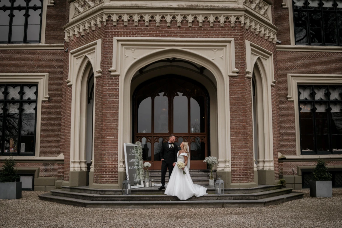 Bruidspaar staat voor een kasteel trouwlocatie